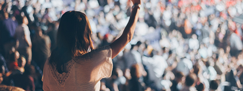 Woman standing in a crowd with her hand up