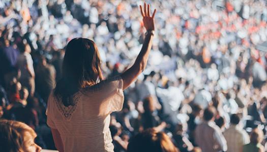 Woman standing in a crowd with her hand up